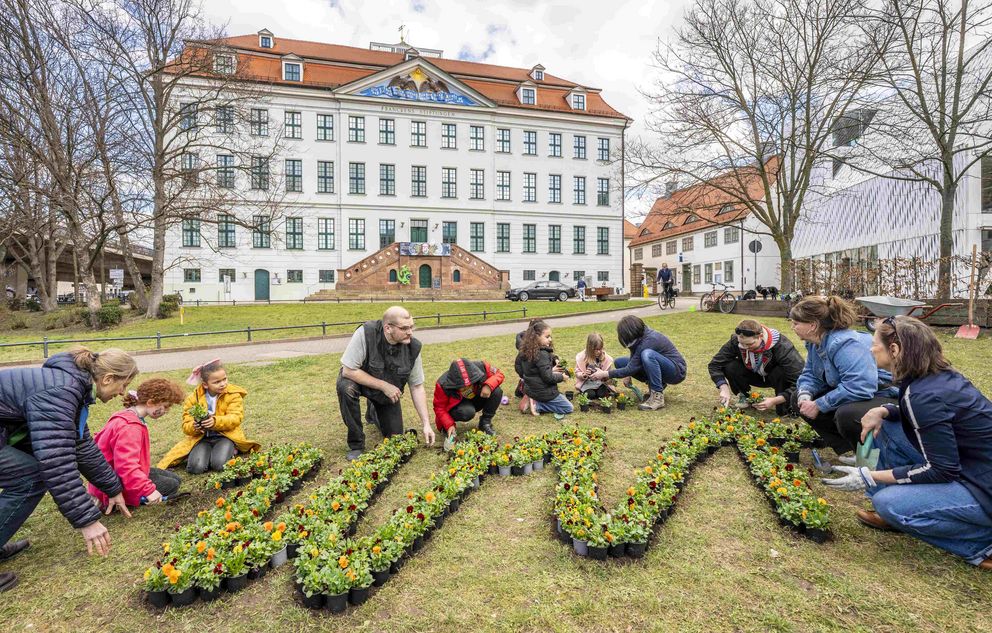 WIR planzen Kinder und Erwachsene pflanzen einen WIR-Schriftzug aus Hornveilchen