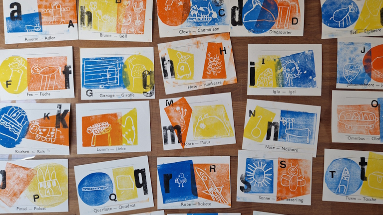 View of the pages of the ABC book, each with one letter and two coloured linocut prints showing animals with the respective initial letter. 