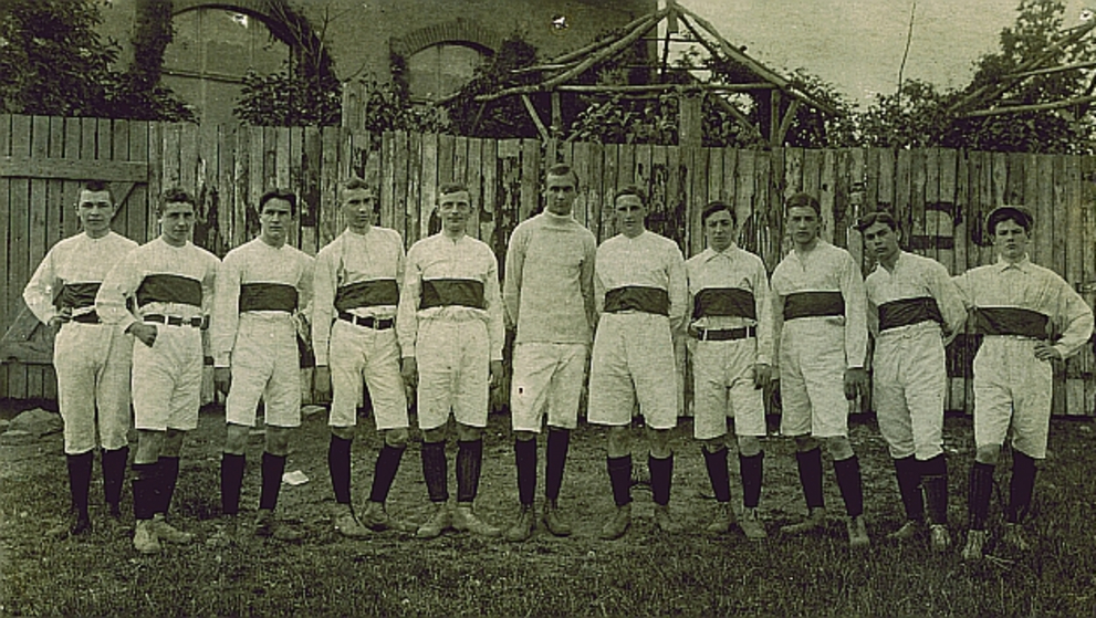 Das Bild zeigt die Fußball-Pokalmannschaft der Oberrealschule der Franckeschen Stiftungen im Jahr 1910. Zu sehen sind junge Sportler in zeittypischen Sportanzügen.