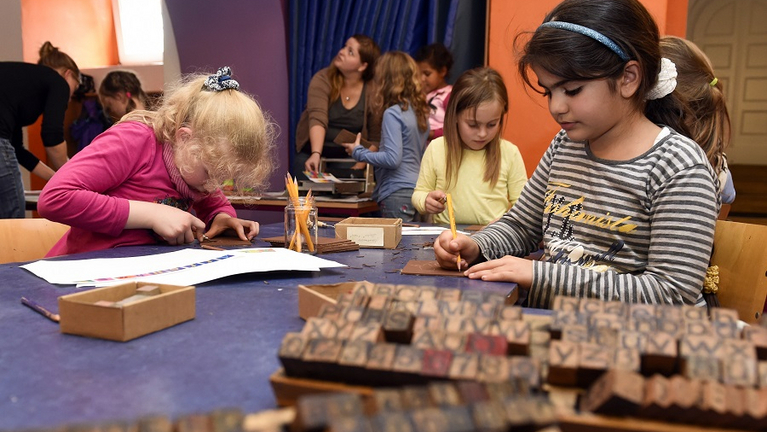 In der Druckwerkstatt erstellen die Kinder aus beweglichen Holzlettern einen Drucksatz für ihre eigenen Geschichten.