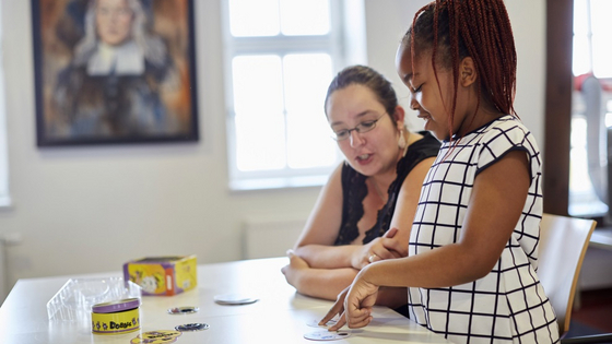 Eine Schülerin verbessert spielerisch ihre Sprachkompetenz. Eine Freiwillige des Familienzentrums hilft ihr dabei.