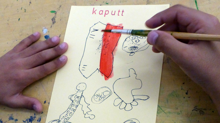 Kinderhände malen mit einem Pinsel Formen, die thematisch zu dem Überbegriff »kaputt« passen