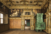 ein Zimmer mit prächtigen goldenen Verzierungen, Wandgemälden und einem großen Kachelofen