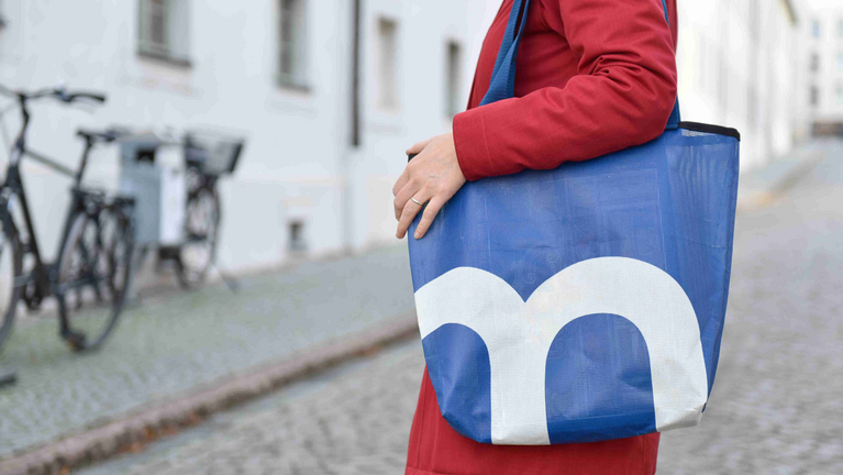 eine Person mit einem blauen Beutel über der Schulter 